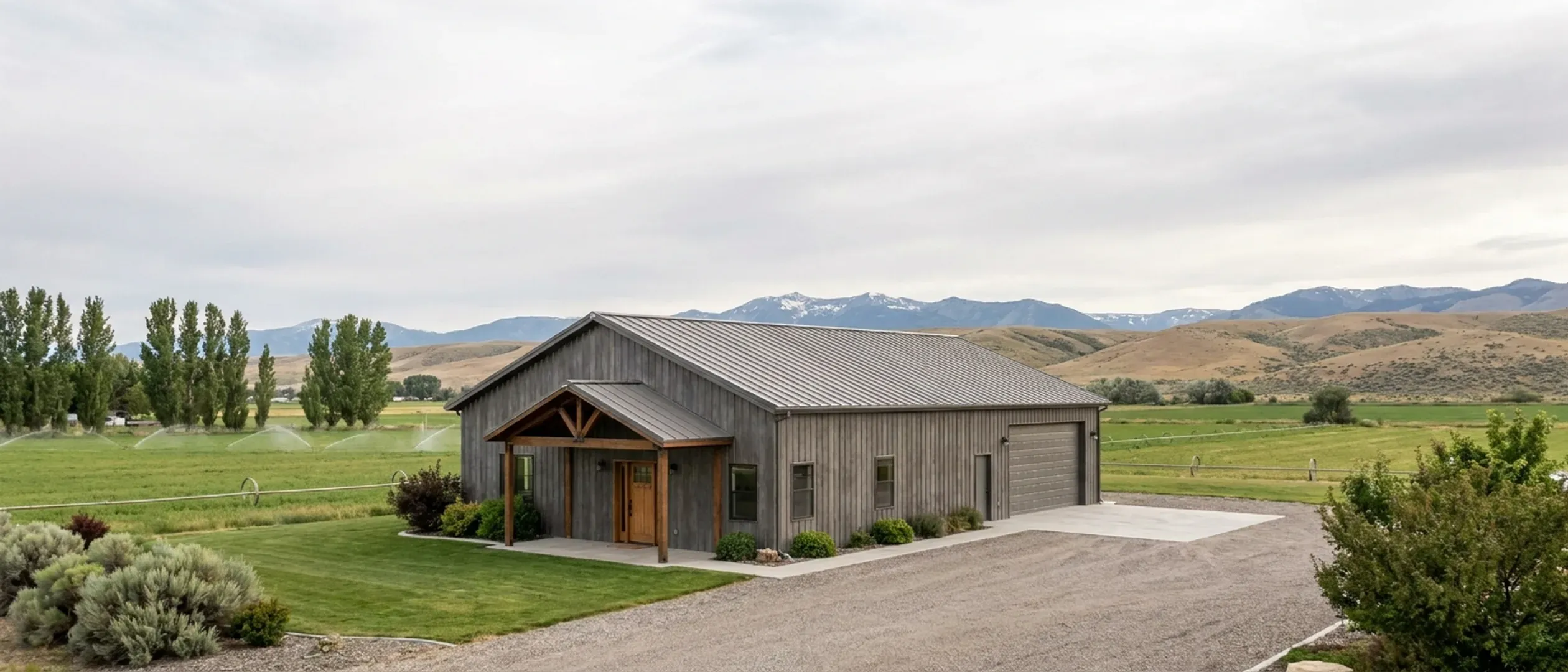 A completed barndominium with a covered entry porch and an attached shop bay, photographed in flat overcast daylight.