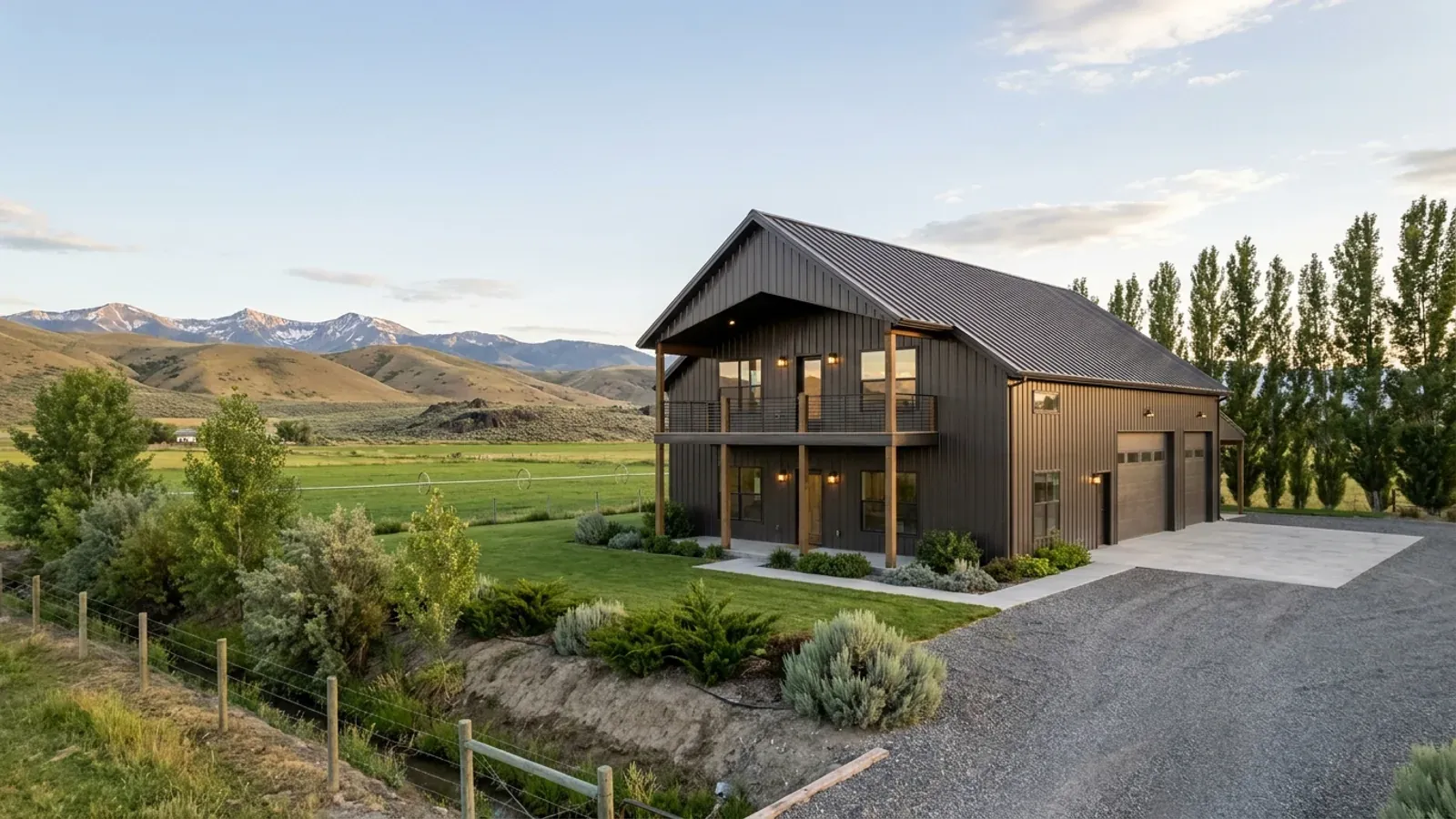 A completed two-story barndominium with visible second-story windows and a small covered balcony above the entry porch.